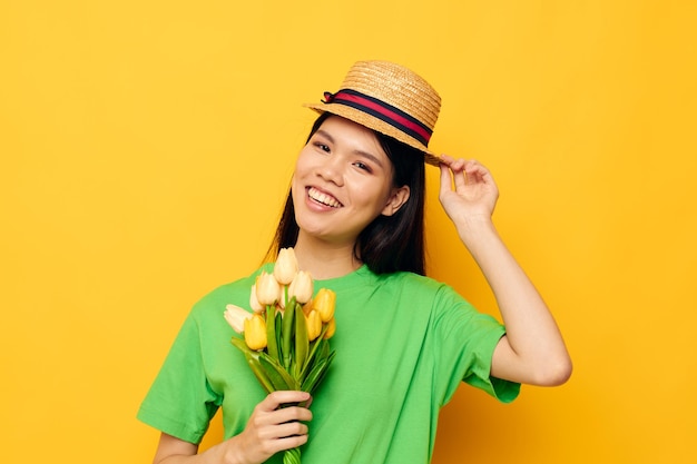 Mulher camiseta verde um buquê de flores amarelas em um chapéu fundo amarelo inalterado