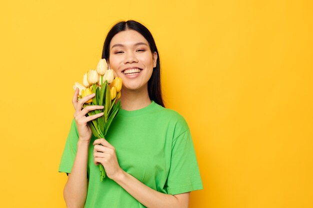 Mulher camiseta verde um buquê de flores amarelas fundo amarelo inalterado