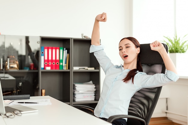 Mulher cansada bocejando no escritório no seu local de trabalho