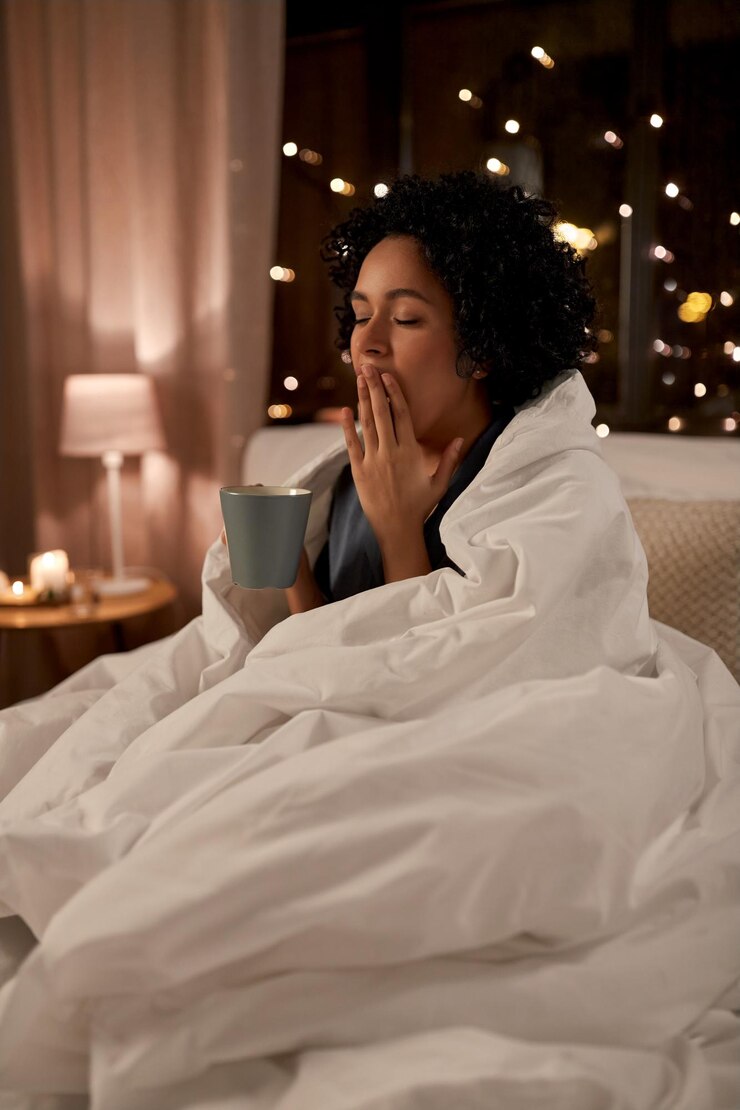 Foto mulher cansada com café bocejando na cama à noite