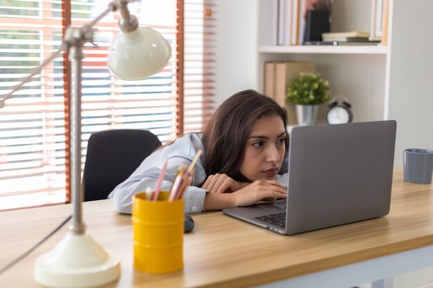 Foto mulher cansada do trabalho e não da inspiração preguiçosa apática garota cansada de aprender olhando para o laptop