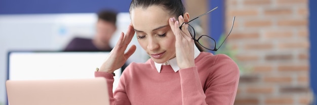 Mulher cansada se senta em sua mesa com os olhos fechados. Estresse e depressão no conceito de trabalho