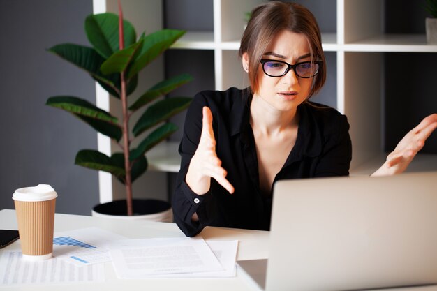 Mulher cansada, trabalhando no computador no escritório