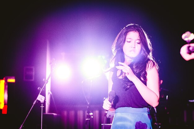 Foto mulher cantando em palco iluminado à noite