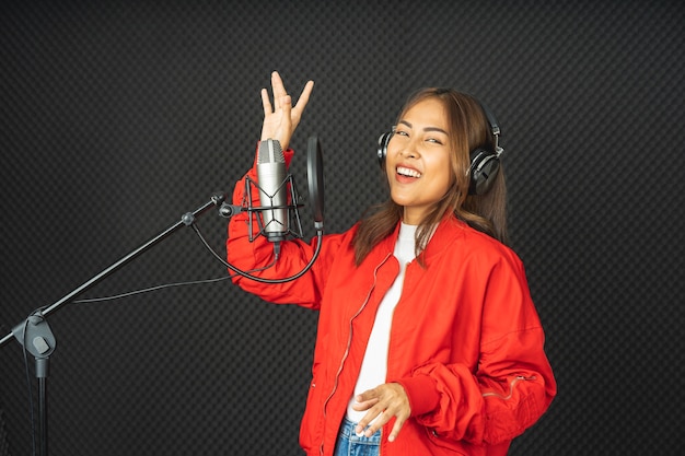 Mulher cantora asiática em um estúdio de gravação usando um microfone de estúdio com paixão em um estúdio de gravação de música