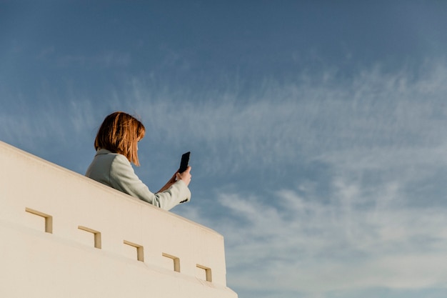 Mulher capturando a vista de Los Angeles com seu telefone no Observatório Griffith, EUA
