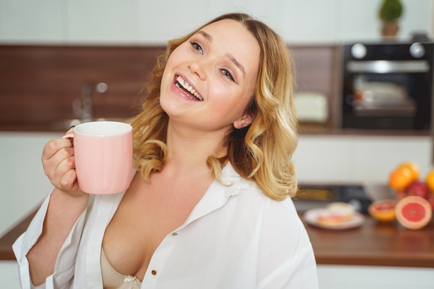 Mulher carinhosa em casa segurando um copo com sua bebida favorita