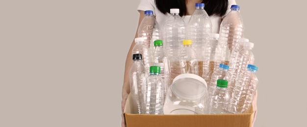Mulher carrega garrafa de plástico reciclada que contém em caixa de papelão para sustentabilidade e meio ambiente A Economize energia e mundo