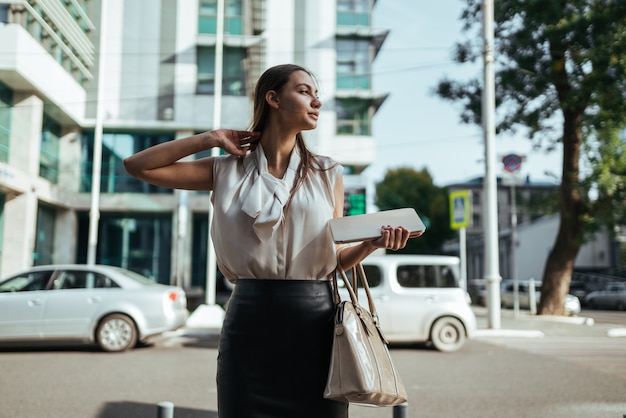 Mulher carrega uma bolsa e um tablet pc com edifícios