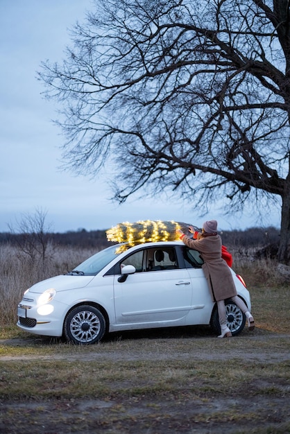 Mulher carregando árvore de natal de carro