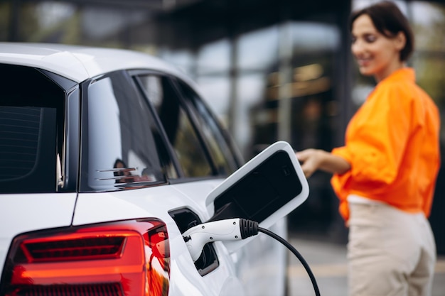 Mulher carregando carro elétrico na estação de carregamento