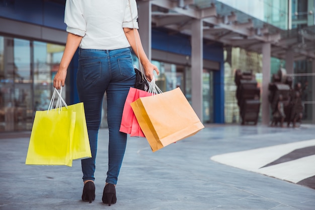 Mulher carregando sacolas de compras enquanto caminha pela rua