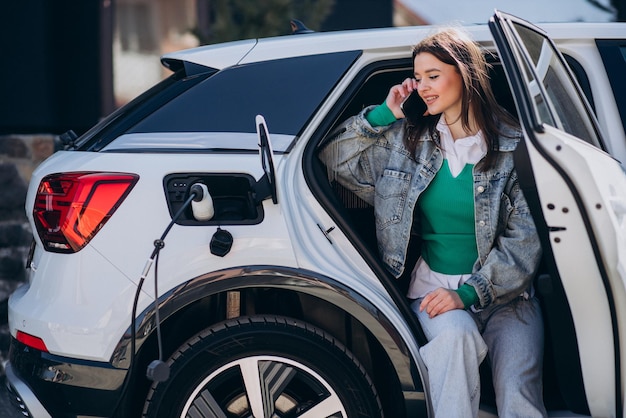 Mulher carregando seu carro elétrico com pistola de carregamento