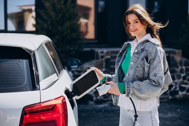 Foto mulher carregando seu carro elétrico com pistola de carregamento