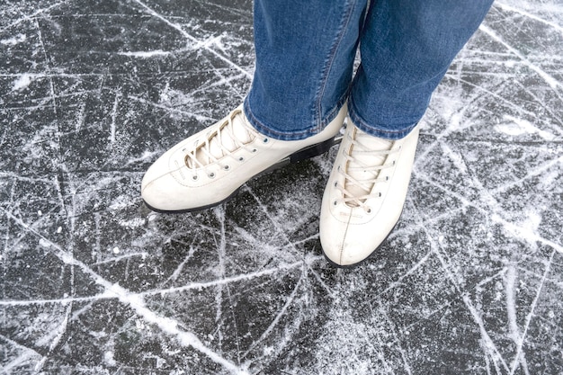 Foto mulher casual olha em patins de gelo e jeans na vista superior de macro de gelo