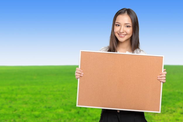 Mulher casual sorridente segurando o quadro de cortiça vazio