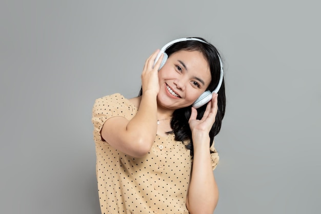 Mulher casual sorrindo enquanto ouve música usando fones de ouvido