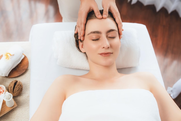 Mulher caucasiana a desfrutar de uma massagem relaxante anti-estresse na cabeça.