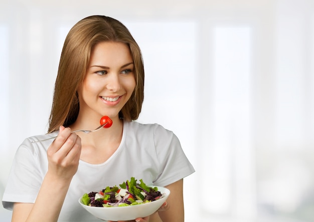 Mulher caucasiana atraente com salada no fundo