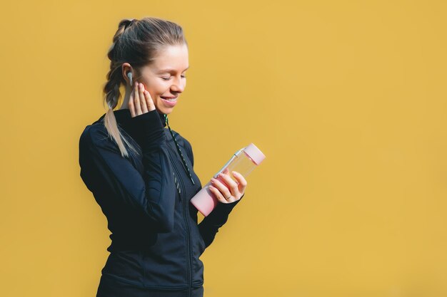 Mulher caucasiana atraente em traje esporte com fones de ouvido sem fio em background vermelho isolado