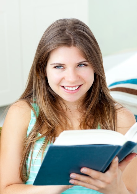 Mulher caucasiana brilhante lendo um livro sentado em um sofá