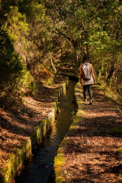 Foto mulher caucasiana caminhando em uma trilha na natureza paisagem de queda paisagem com um rio