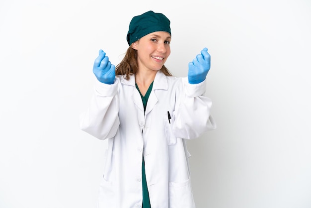 Mulher caucasiana cirurgiã de uniforme verde isolada no fundo branco fazendo gesto de dinheiro