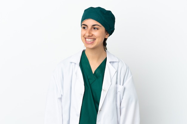 Mulher caucasiana cirurgiã isolada no fundo branco, olhando para o lado e sorrindo