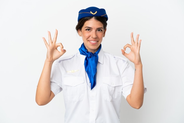 Mulher caucasiana com aeromoça de avião isolada no fundo branco mostrando um sinal de ok com os dedos