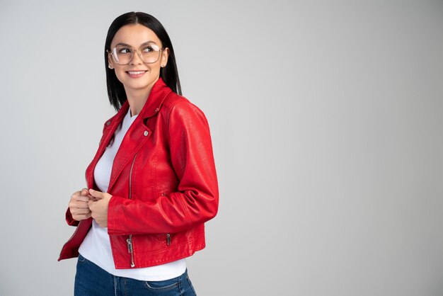 Mulher caucasiana confiante em pé pronta para a ação, desviando o olhar com um leve sorriso. Linda senhora milenar com roupa elegante, posando contra um fundo cinza