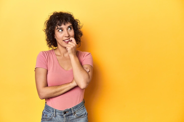 Foto mulher caucasiana de cabelos rizados com camisa rosa relaxada pensando em algo olhando para um espaço de cópia