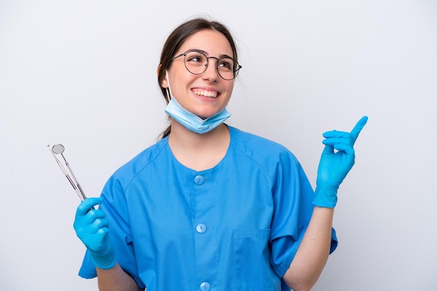 Mulher caucasiana de dentista segurando ferramentas isoladas no fundo branco apontando para uma ótima ideia