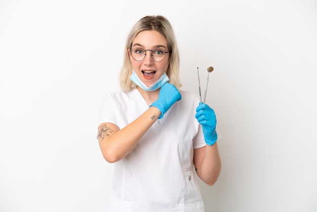 Mulher caucasiana de dentista segurando ferramentas isoladas no fundo branco, comemorando uma vitória