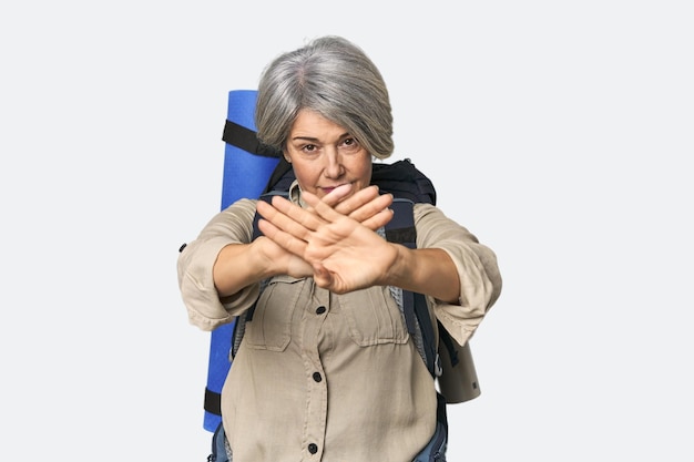 Mulher caucasiana de meia-idade com equipamento de caminhada fazendo um gesto de negação