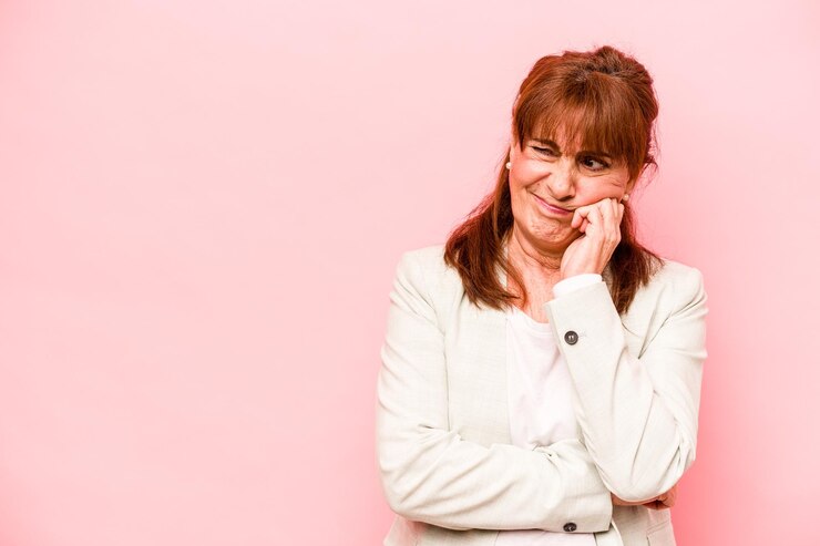 Foto mulher caucasiana de meia-idade isolada em fundo rosa que se sente triste e pensativa olhando para o espaço da cópia