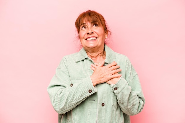 Mulher caucasiana de meia-idade isolada em fundo rosa tem expressão amigável pressionando a palma da mão no peito Conceito de amor