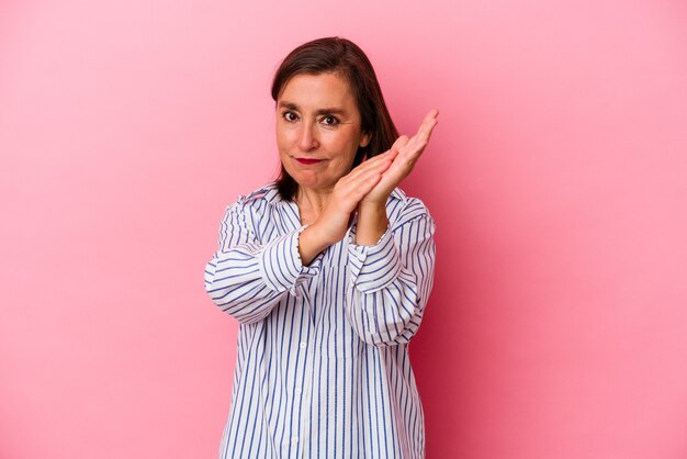 Mulher caucasiana de meia-idade isolada em um fundo rosa, sentindo-se enérgica e confortável, esfregando as mãos confiantes.