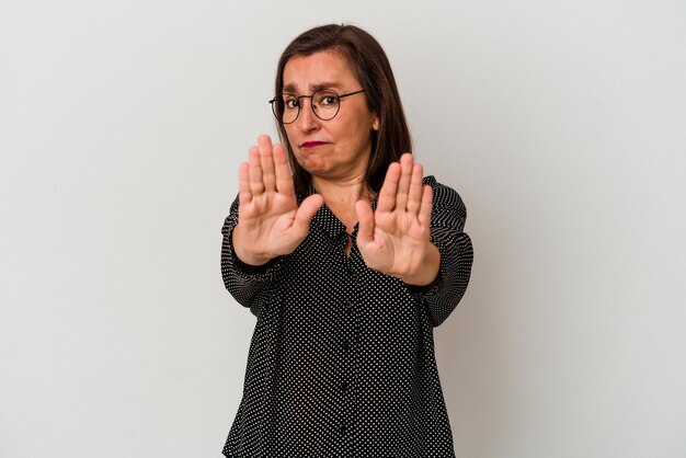 Mulher caucasiana de meia-idade isolada no fundo branco em pé com a mão estendida, mostrando o sinal de pare, impedindo você.