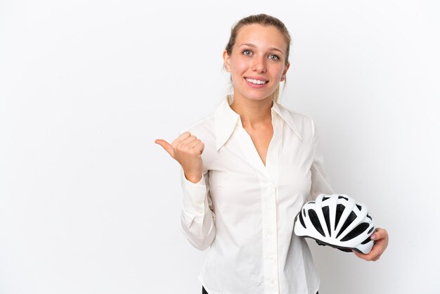 Mulher caucasiana de negócios com um capacete de bicicleta isolado no fundo branco, apontando para o lado para apresentar um produto