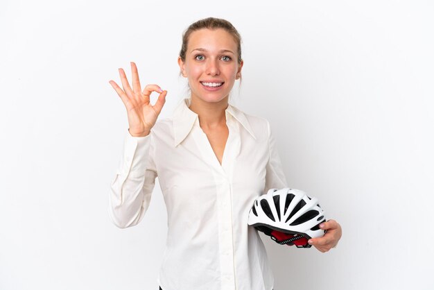 Mulher caucasiana de negócios com um capacete de bicicleta isolado no fundo branco, mostrando sinal de ok com os dedos