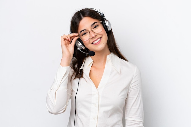 Mulher caucasiana de telemarketing trabalhando com um fone de ouvido isolado no fundo branco com óculos e feliz
