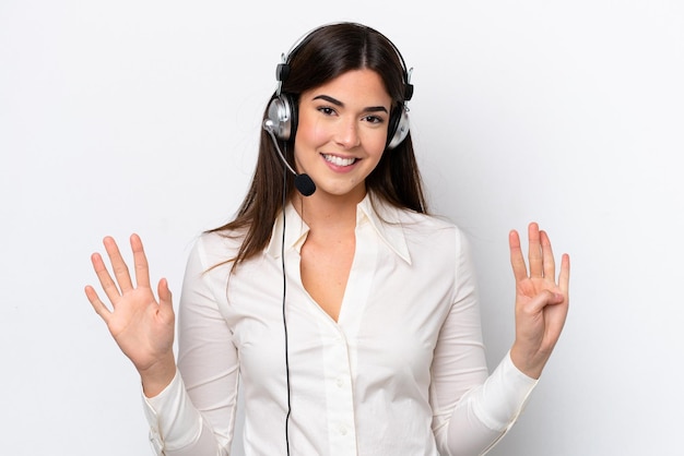 Mulher caucasiana de telemarketing trabalhando com um fone de ouvido isolado no fundo branco contando nove com os dedos