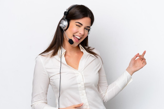 Mulher caucasiana de telemarketing trabalhando com um fone de ouvido isolado no fundo branco, fazendo gesto de guitarra