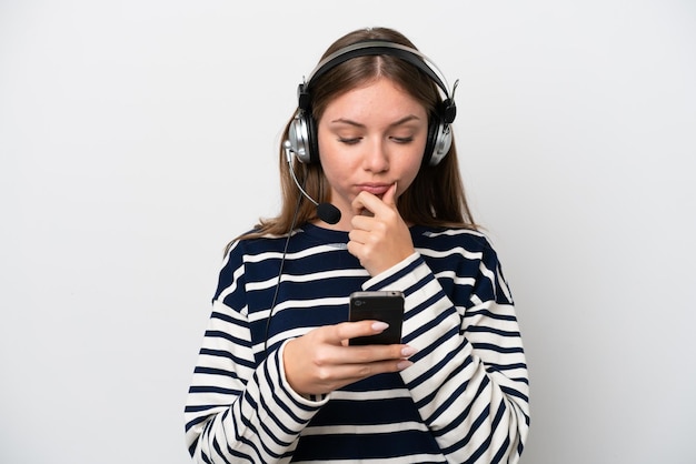 Mulher caucasiana de telemarketing trabalhando com um fone de ouvido isolado no fundo branco pensando e enviando uma mensagem