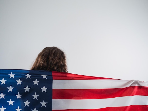 Mulher caucasiana de trás segurando a bandeira dos EUA em fundo branco