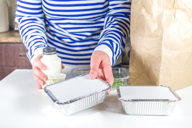 Mulher caucasiana, desmontar o pacote com caixas de refeição para aquecer e comer do restaurante. Conceito de comida para serviço de entrega de pedidos de comida para viagem, close-up