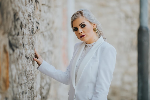 Mulher caucasiana elegante elegante em um terno branco bonito e calças posando para sessão de fotos de moda