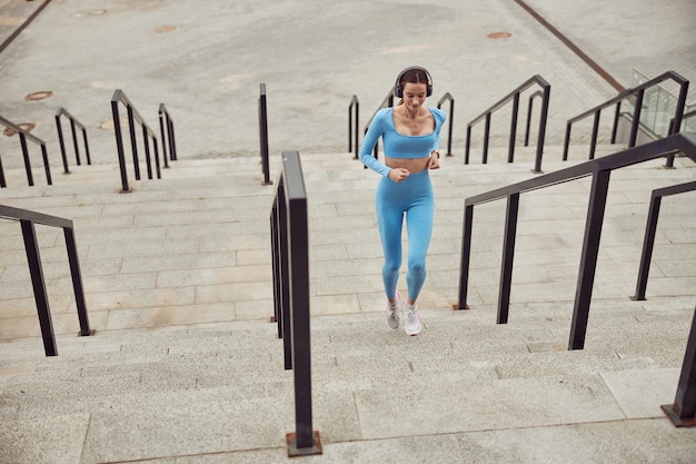 Mulher caucasiana em forma bonita fazendo exercícios ao ar livre na cidade