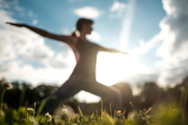 Mulher caucasiana em forma desportiva fazendo asana Virabhadrasana 2 postura de guerreiro na natureza