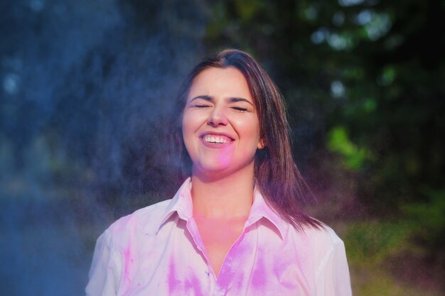 Mulher caucasiana emocional brincando com uma explosão de tinta rosa e azul Holi